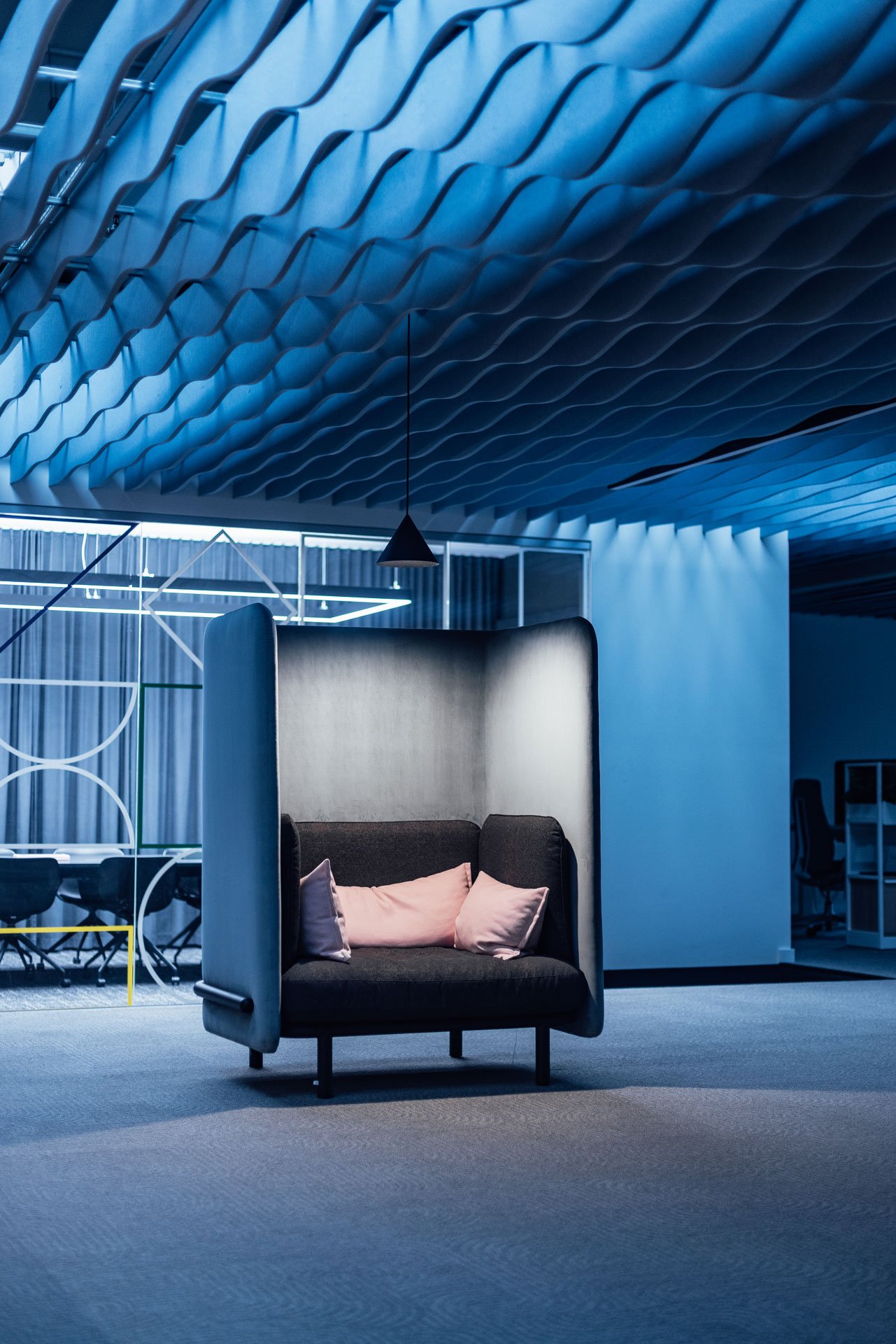 Blaues Sofa mit Akustikschirm unter blauen Akustikbaffeln