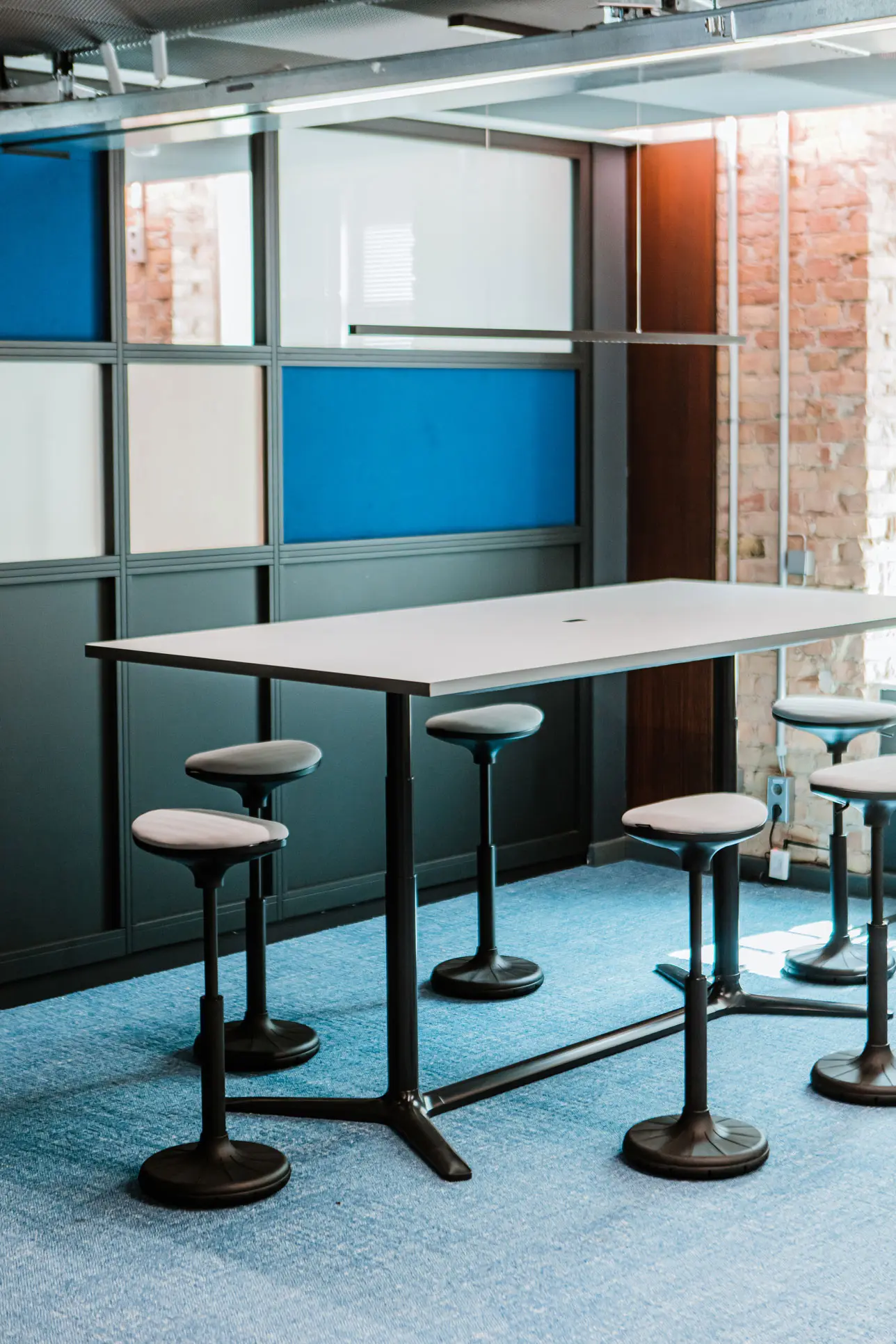 Adhoc Meetingraum mit blau-weißen Akustikpaneelen und Sitzhockern