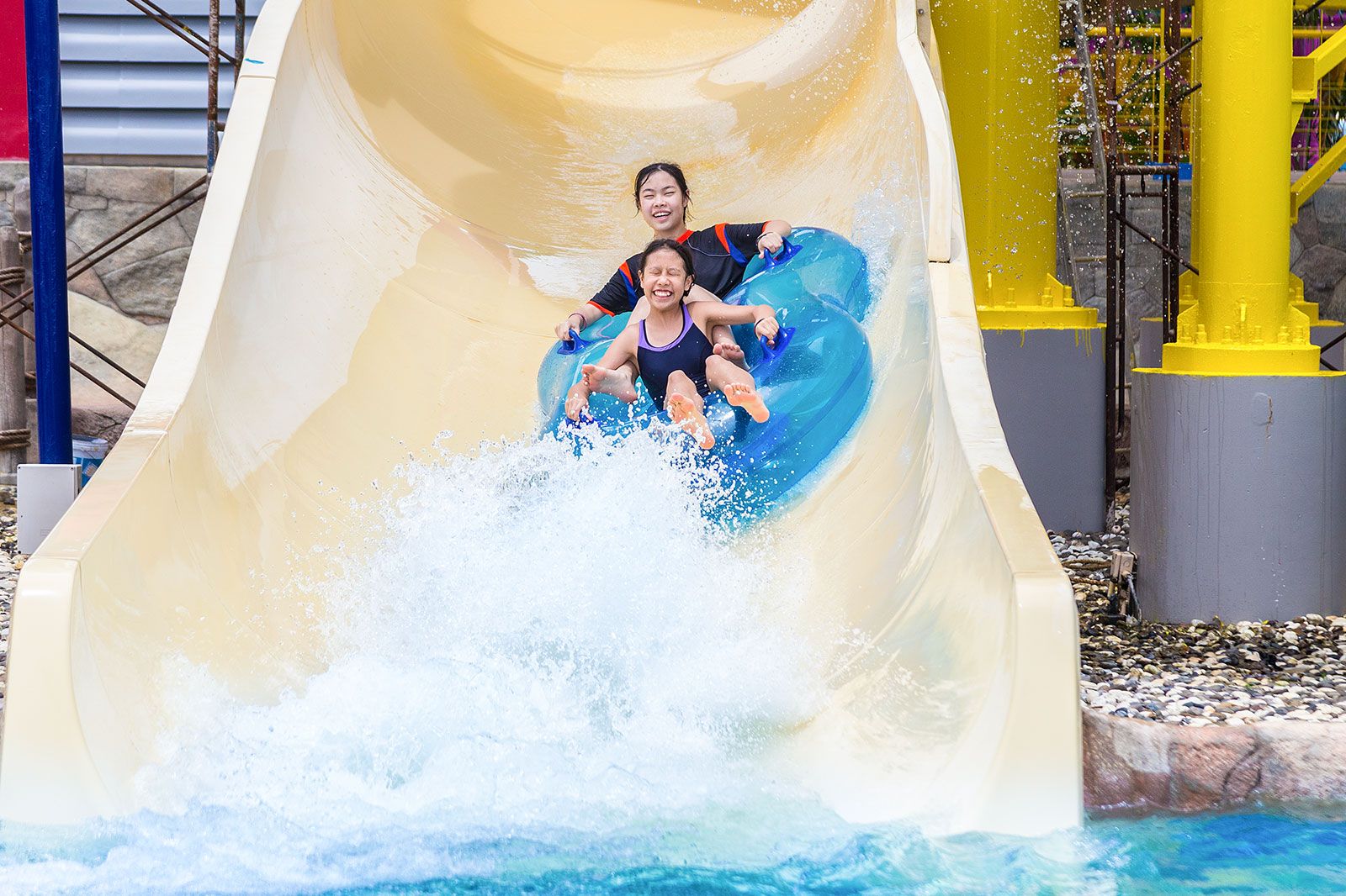 Two women coming down through a waterslide.