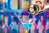 A shaker pouring a blue martini.