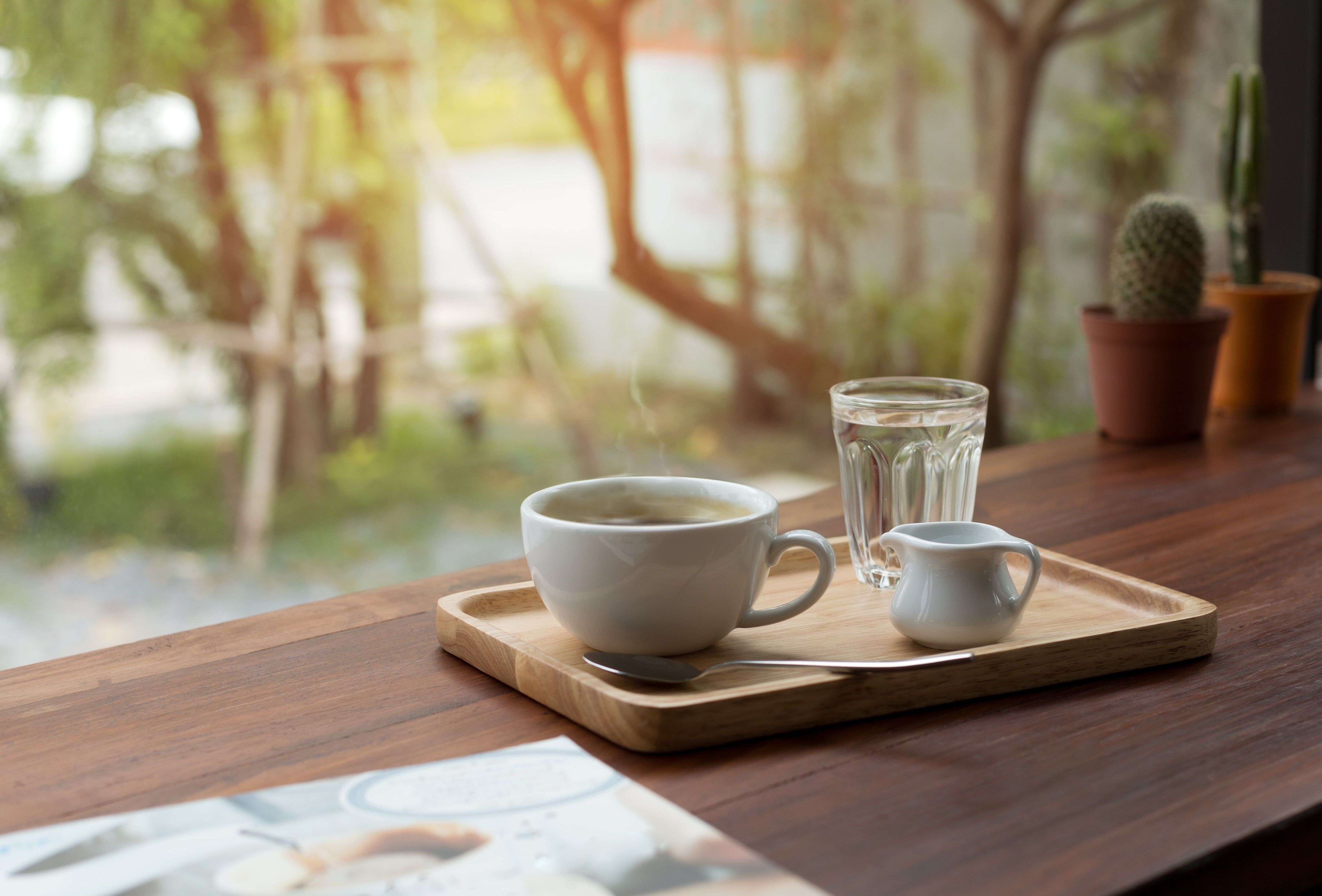 Steaming cup of coffee with water and cream.
