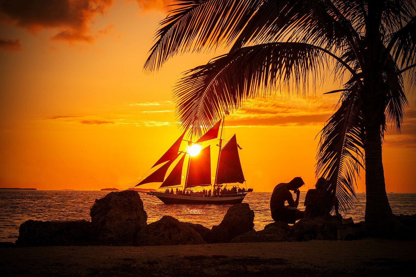 People watching a boat at sunset.