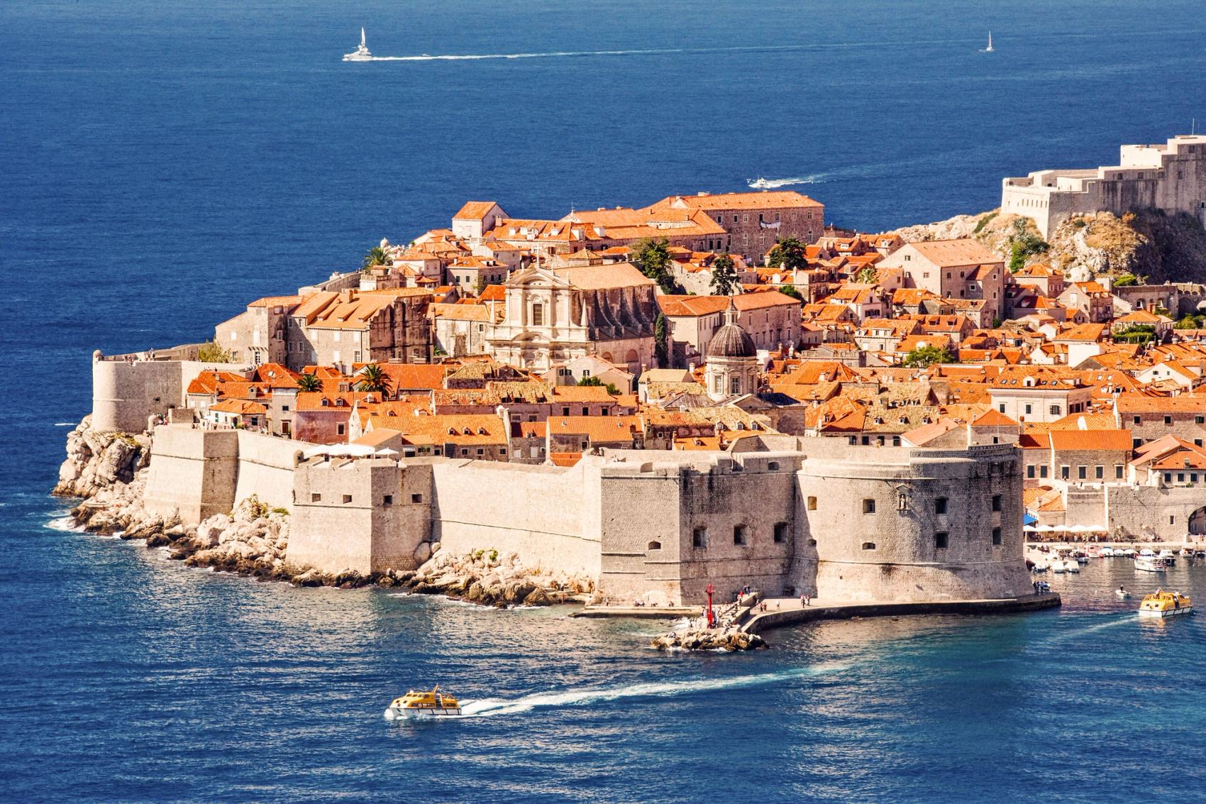 Distant view of fortified town surrounded by water.