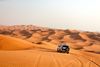 A car drives over many sand dunes