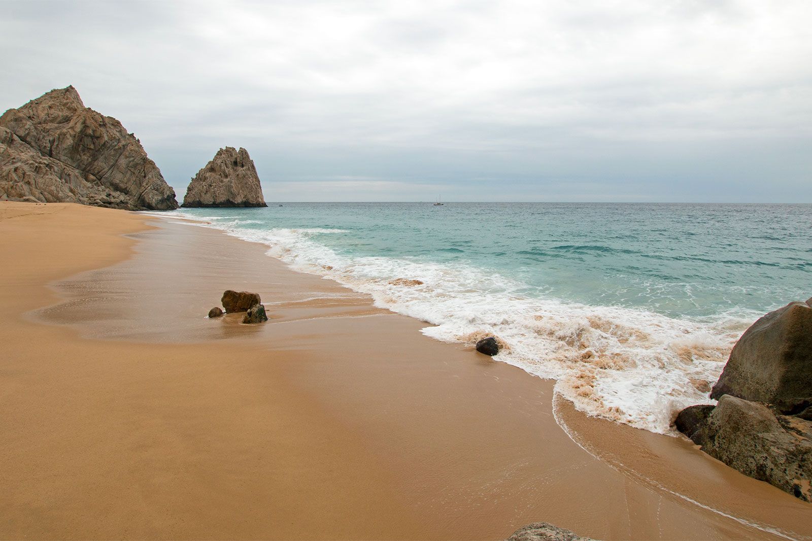 A rocky sandy beach with calm waves.