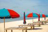 Red and blue umbrellas on the beach with wooden benches on Biloxi Beach in Mississippi.