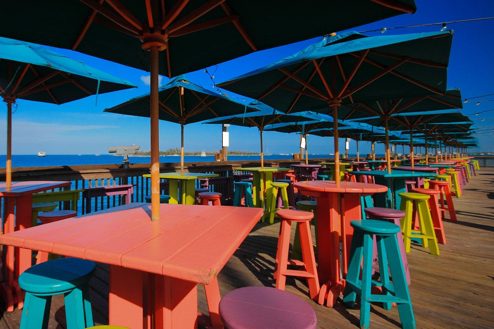 Colorful tables on a pier over the water.