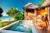 A hot tub jacuzzi by a tropical beach with a wood deck and lounge chairs and a palapa thatched structure.