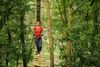 A woman climbing a rope bridge in the adventure park.