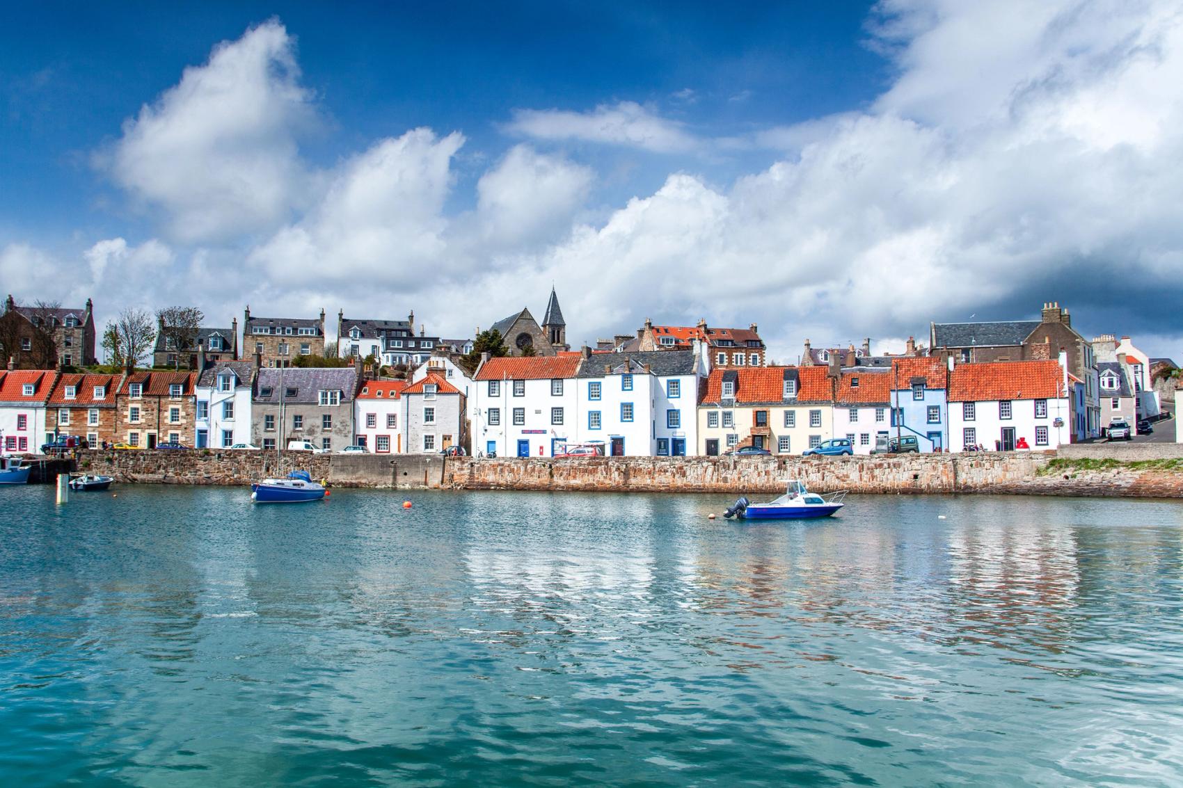 View from the water of some boats and two and three story dwellings along the edge of the water.