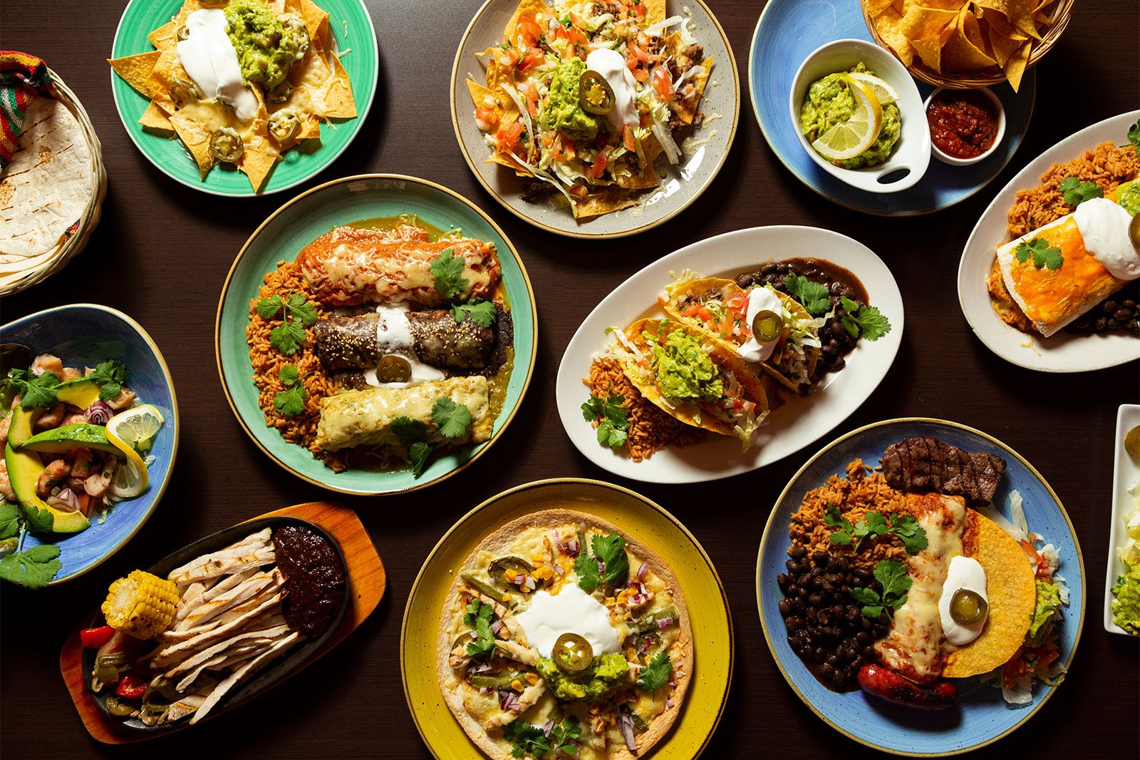 Typical mexican food, tacos, tamales, guacamole, tostadas on a wooden background.