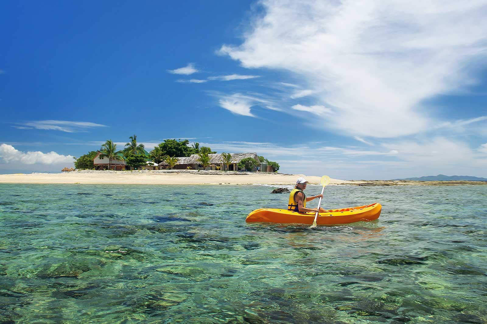 A kayaker paddling in the ocean with an island in the background.