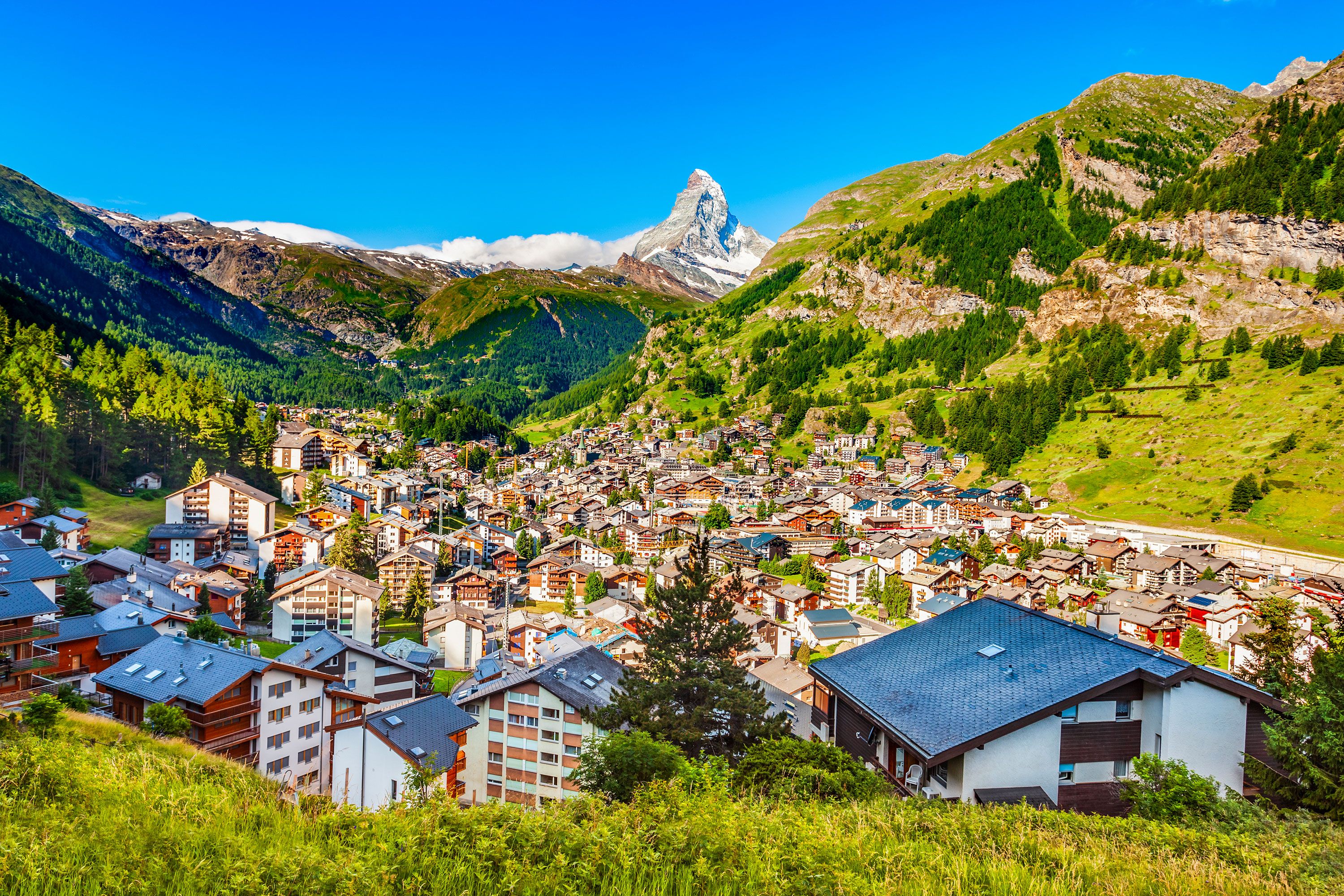 Traditional chalets and apartment buildings in Zermatt, Switzerland with the Matterhorn in the distance.