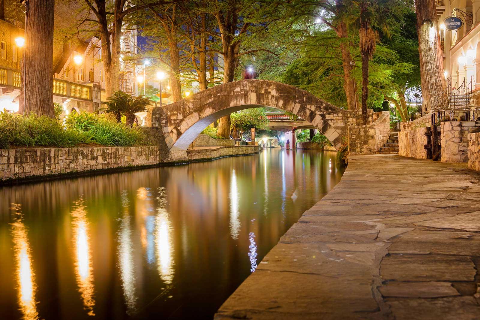A stone arch bridge on a river in evening lights.