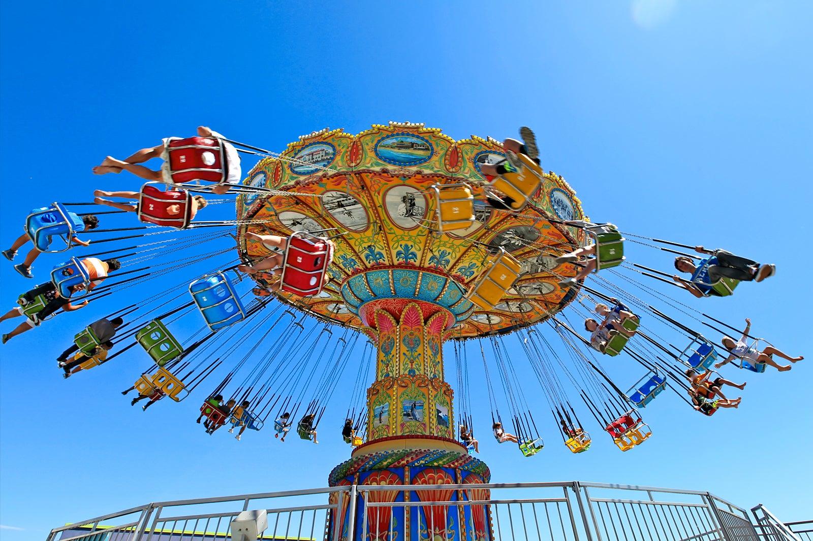 Multi-colored amusement park ride with people on flying swings.
