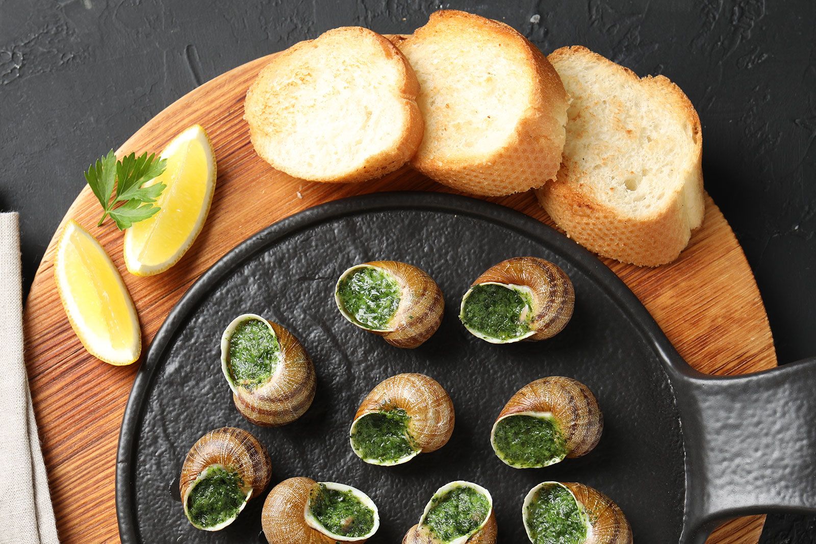 A cooked snails kept on a table along with bread.