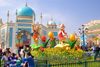 A group of female friends sitting in front of a Cartoon statue and a blue building in a theme park.