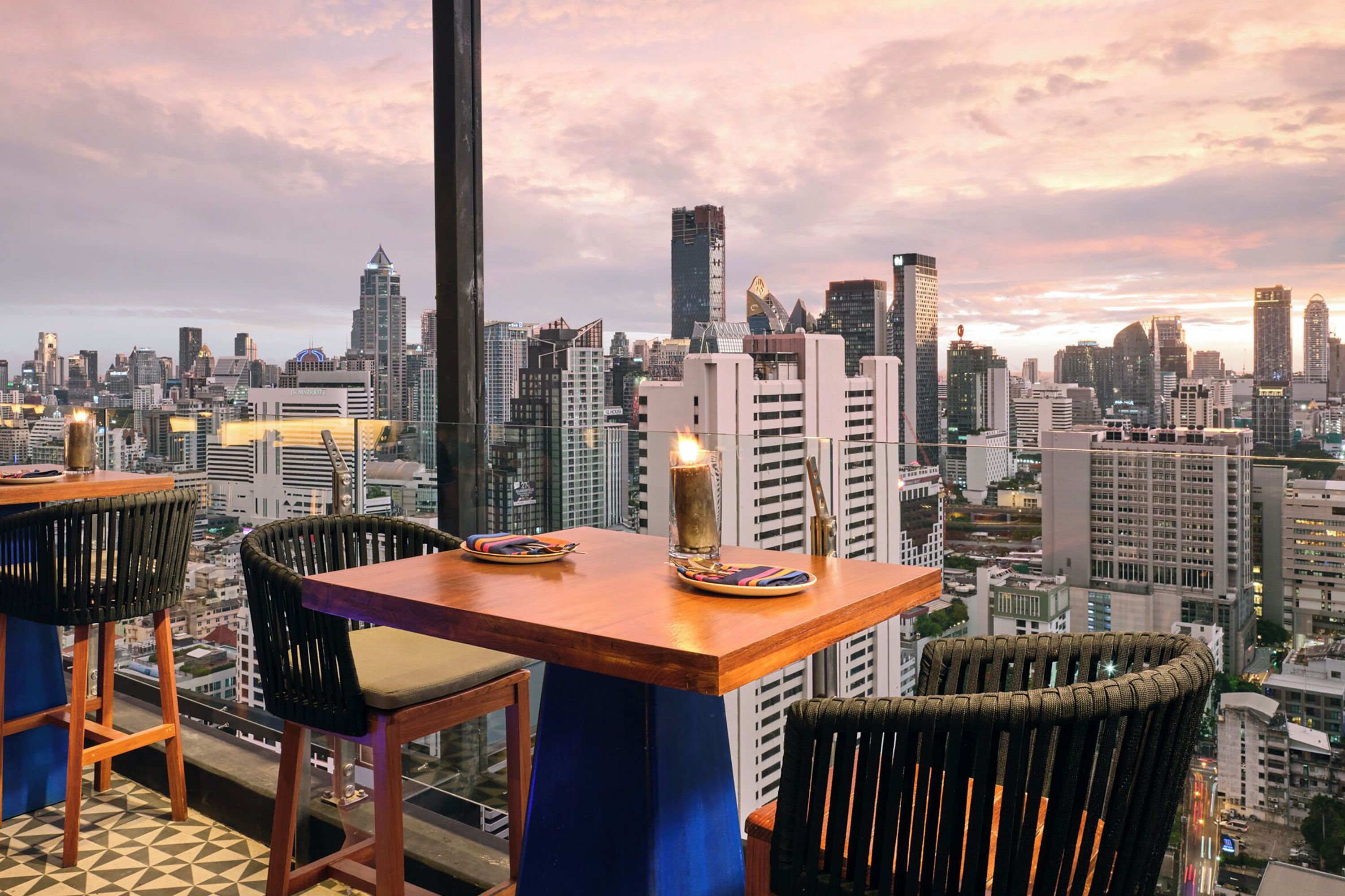 Chairs and tables next to a glass window overlooking a city.