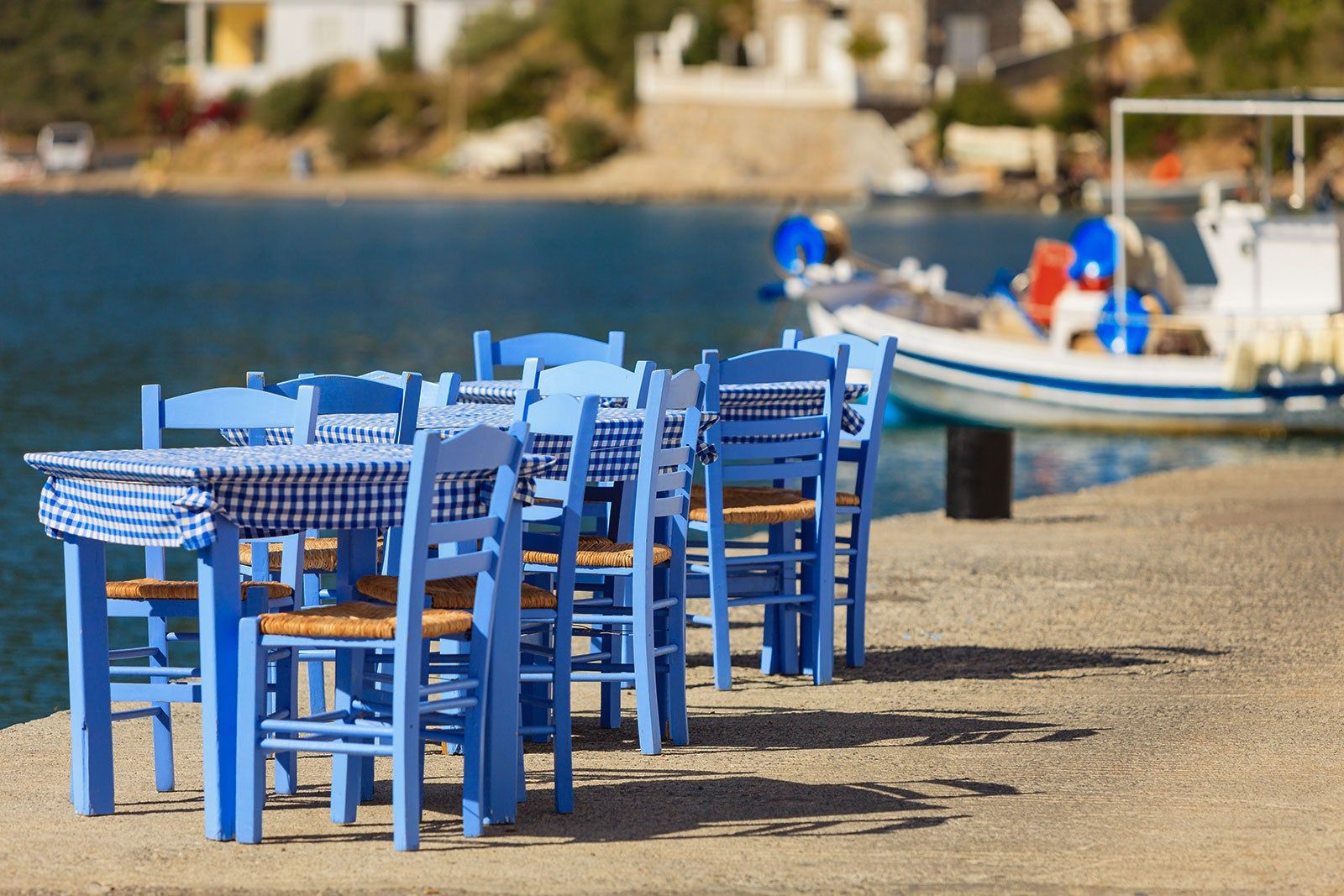 Blue tables set up for dining on a pier. 