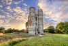 Stone towers of a castle in a green field.