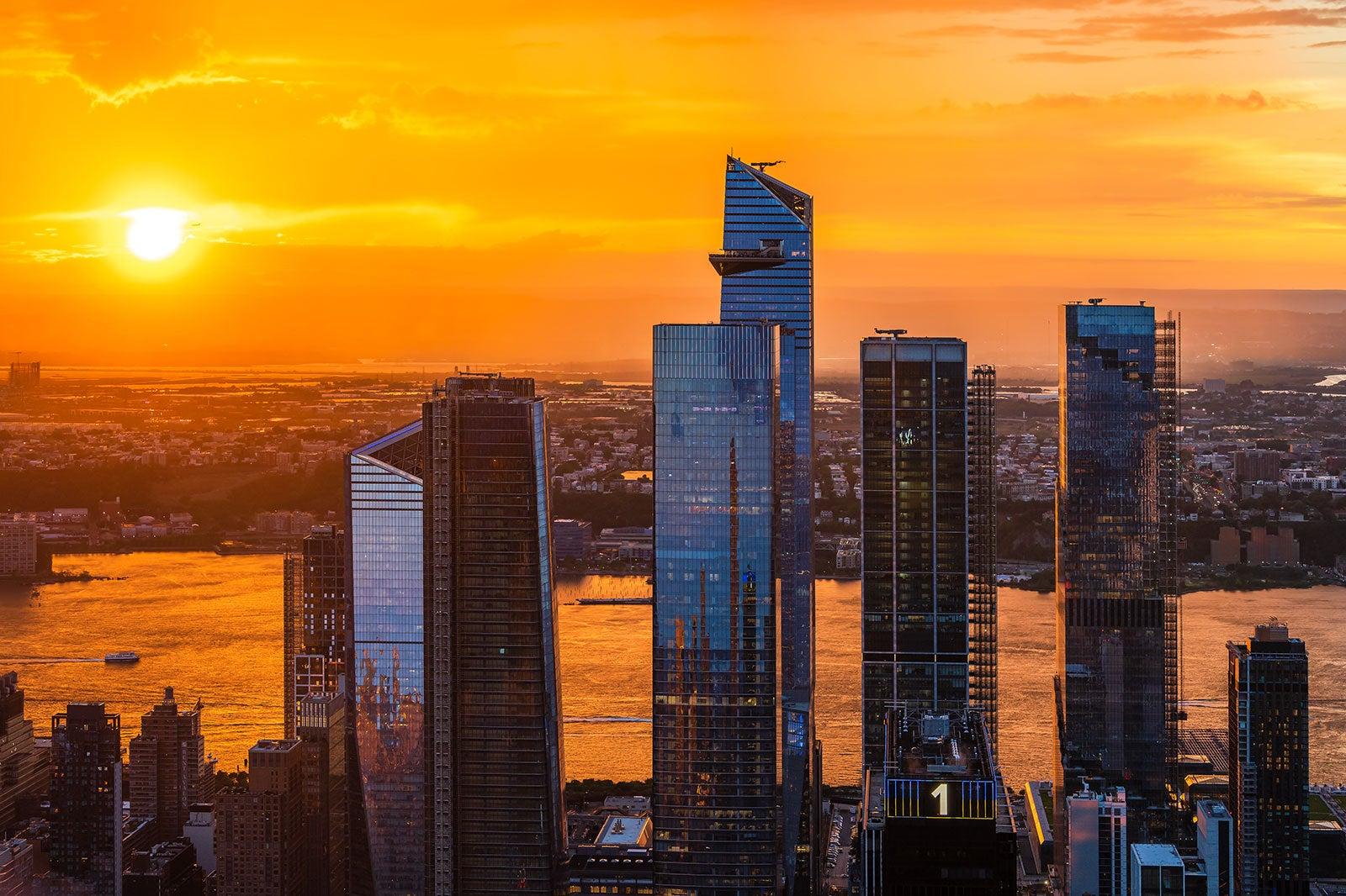 Silhouette of a city with tall buildings at sunset.
