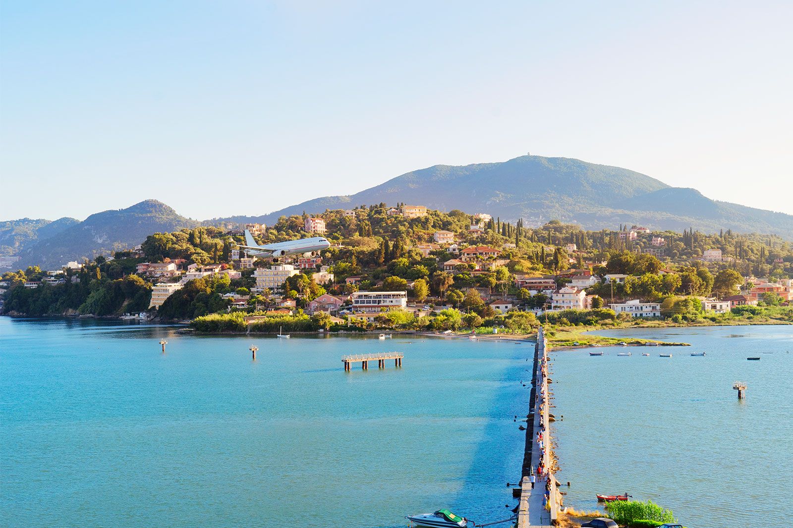 A coastal beach town with an airplane leaving the coast.