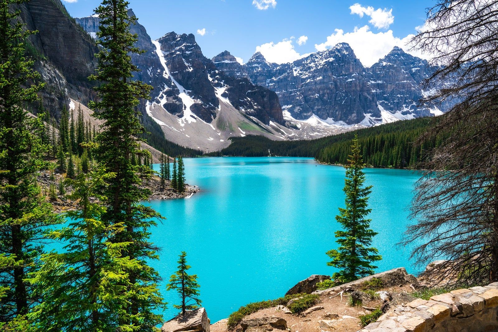 Bright blue water surrounded by mountains and trees.