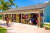 Colorful outdoor souvenir market with palm trees and shoppers on a sunny day.