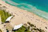 An above view of a shade area and beachgoers on the beach.