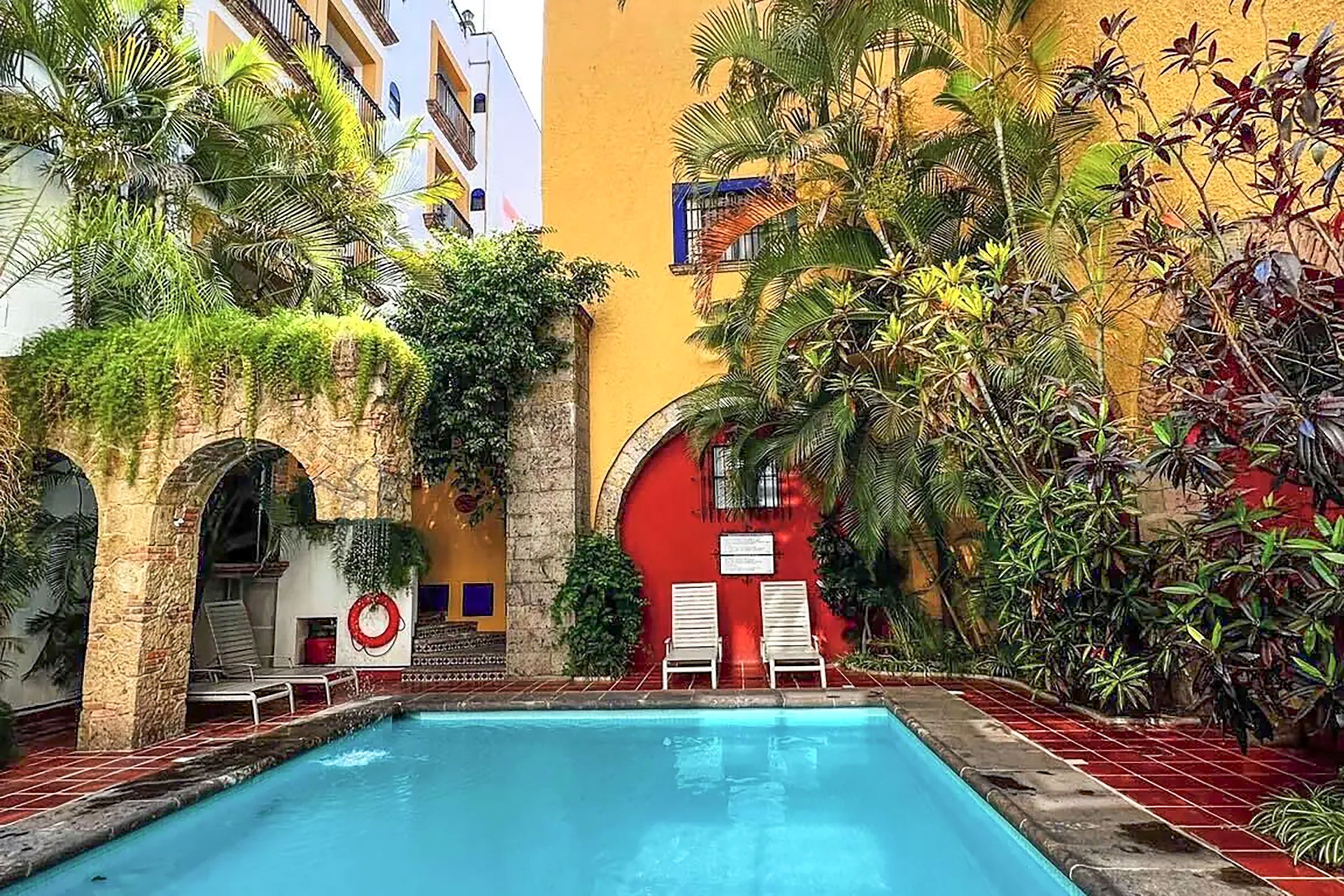 An interior courtyard featuring a swimming pool and lush vegetation and bright blue sky.