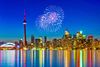 Toronto skyline with fireworks reflected on Lake Ontario.