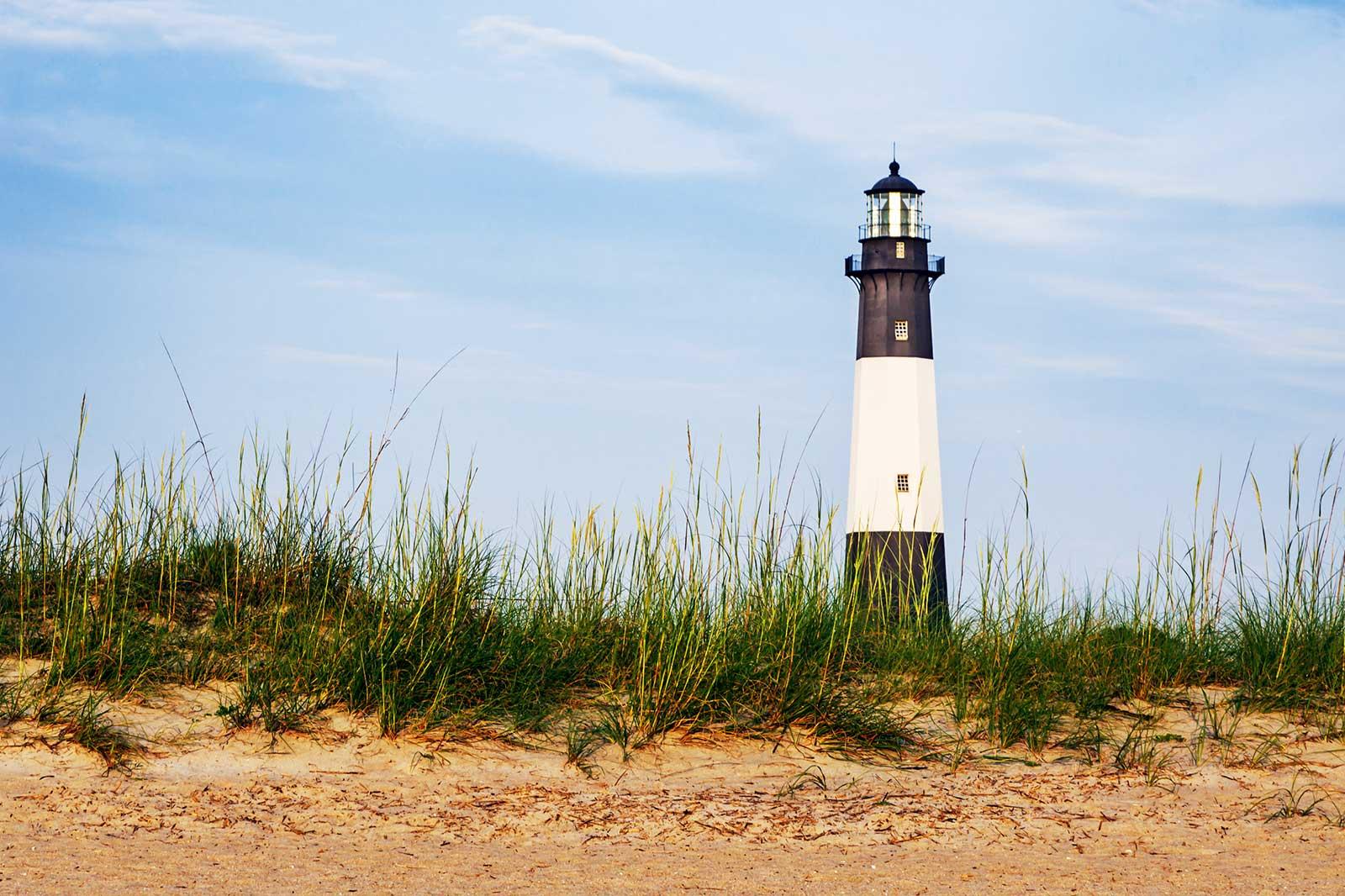 A black and white lighthouse at a beach.