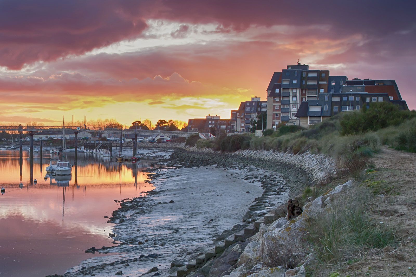 A sunset over a creek with boats.
