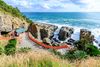 A temple with red fencing along a coastal cliff.