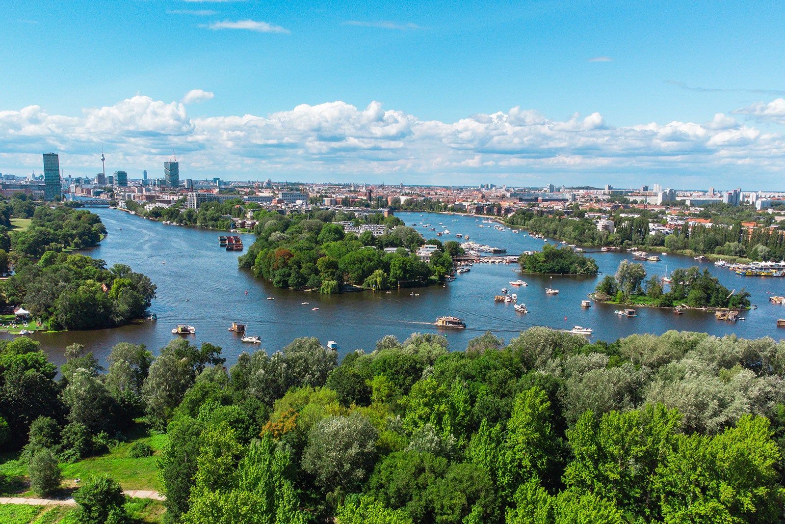 Berlin skyline with the river Spree and dotted with leafy trees.