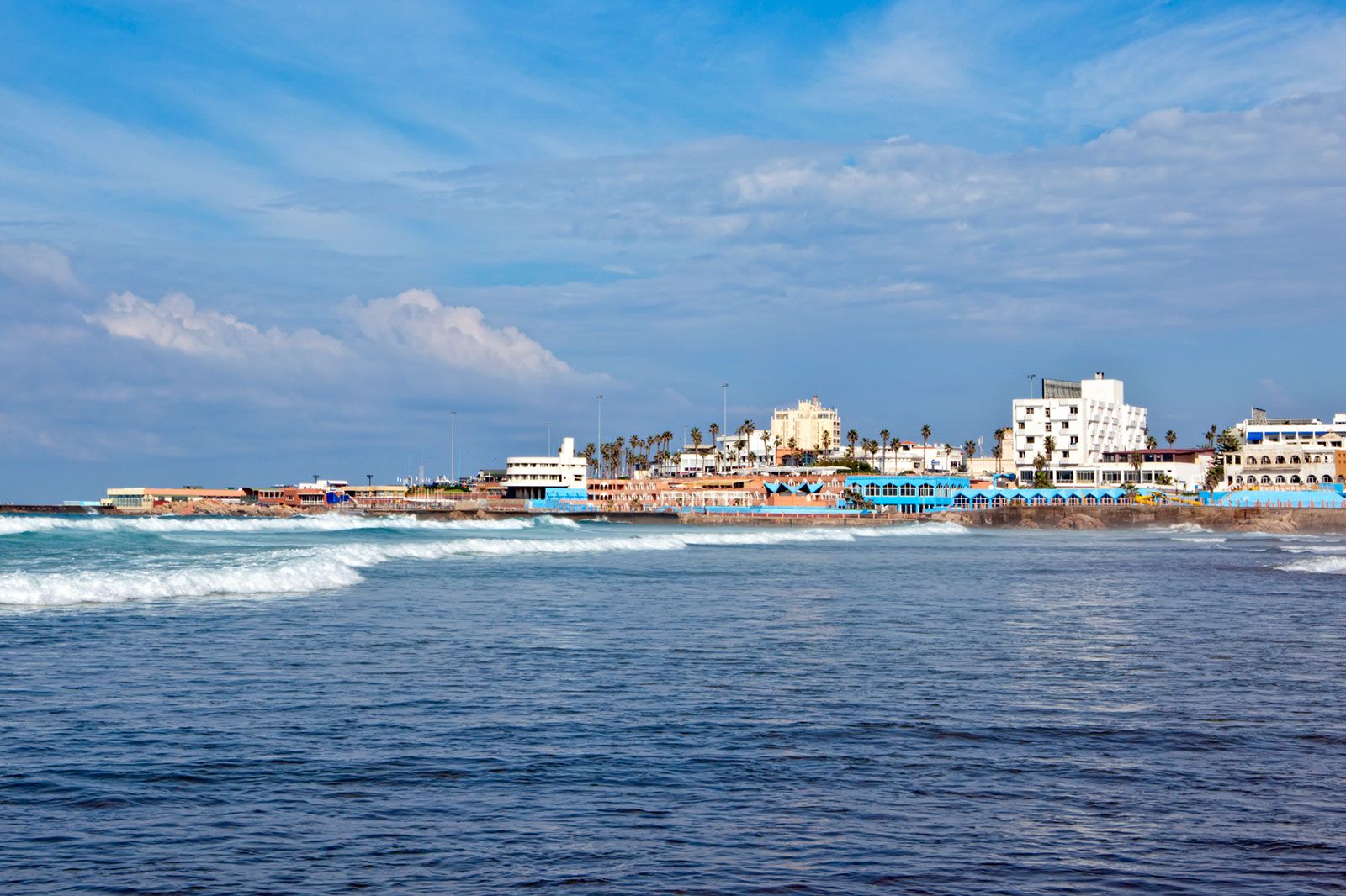 A beach, ocean, and a city in the background.