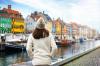 Rear view of a woman wearing a winter hat with the colorful buildings of Nyhavn, Denmark during Christmas.