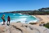 People on a hiking path above a beach and ocean view.