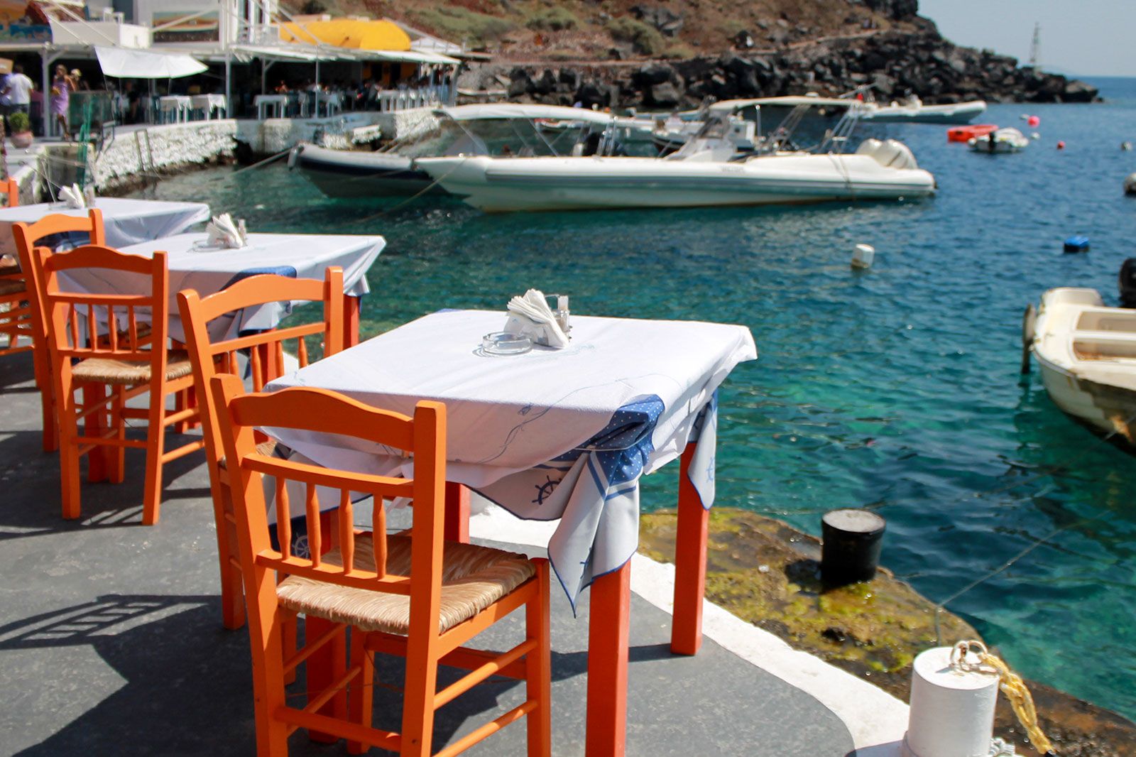 White tables overlooking a beach cove with boats.