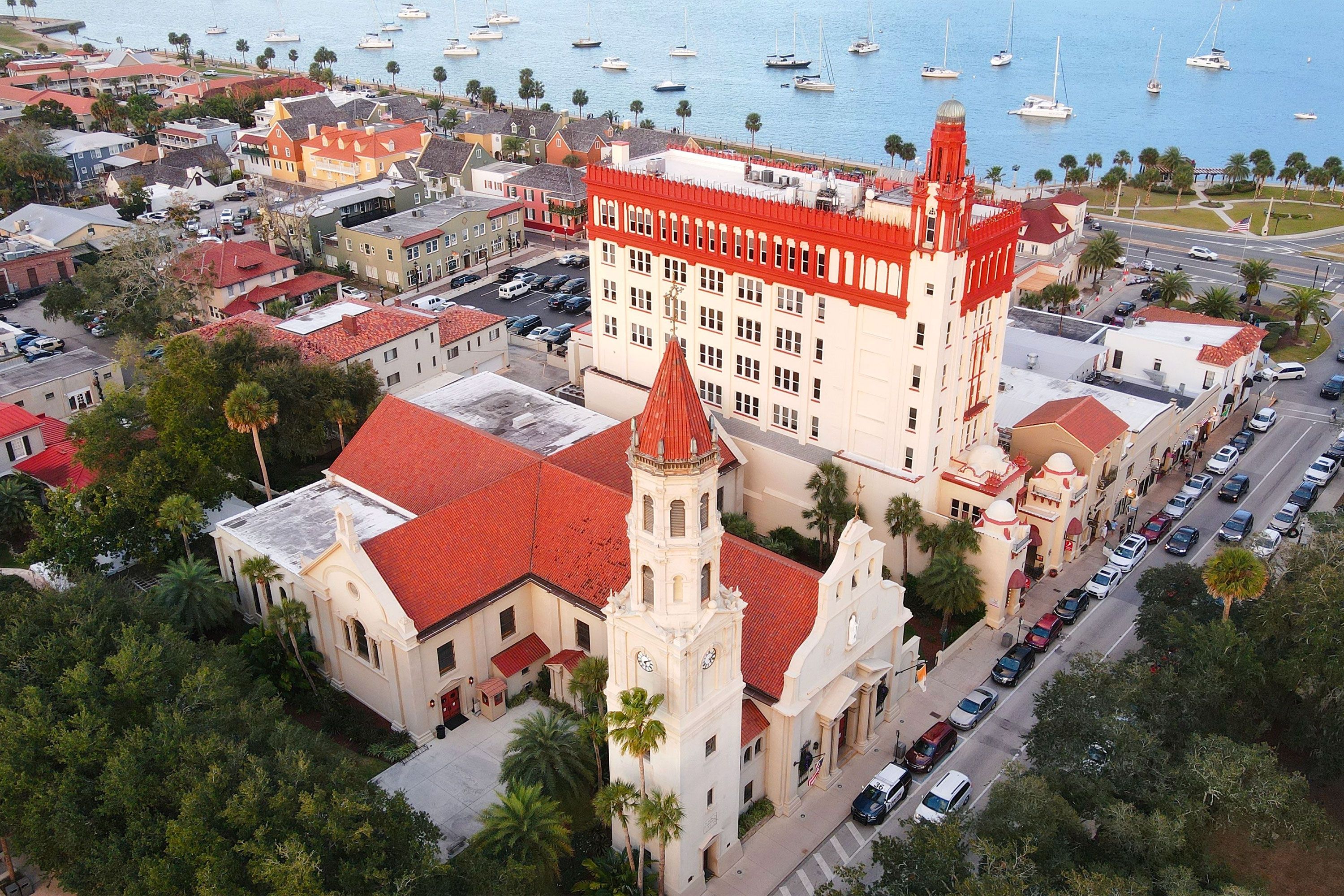 An aerial view of a Cathedral with a red roof next to a harbor.