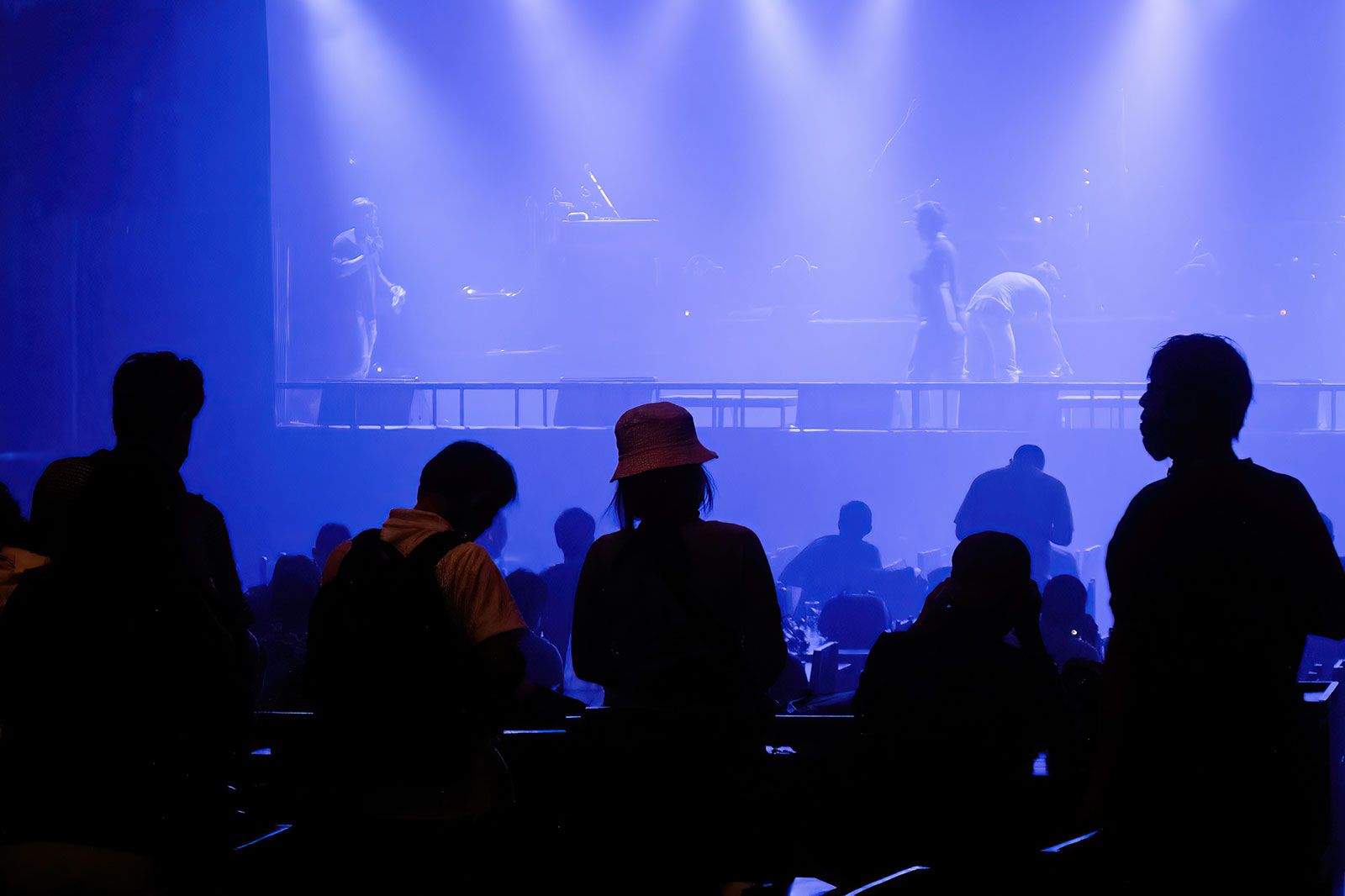 A silhouette of a crowd in front of stage lights.
