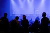 A silhouette of a crowd in front of stage lights.