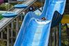 A couple sliding down a blue water slide.