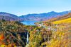 A view of lake with a waterfall surrounded by forest in autumn.