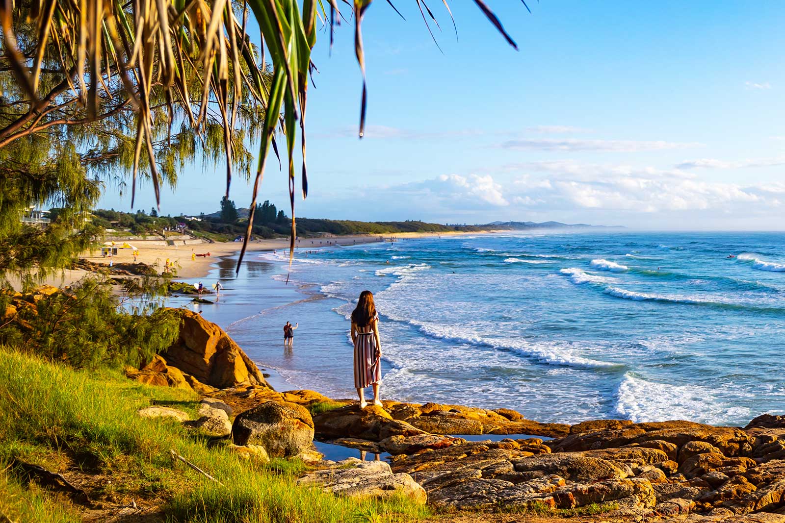 Woman looks out over a beach and ocean waves.