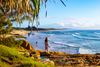 Woman looks out over a beach and ocean waves.
