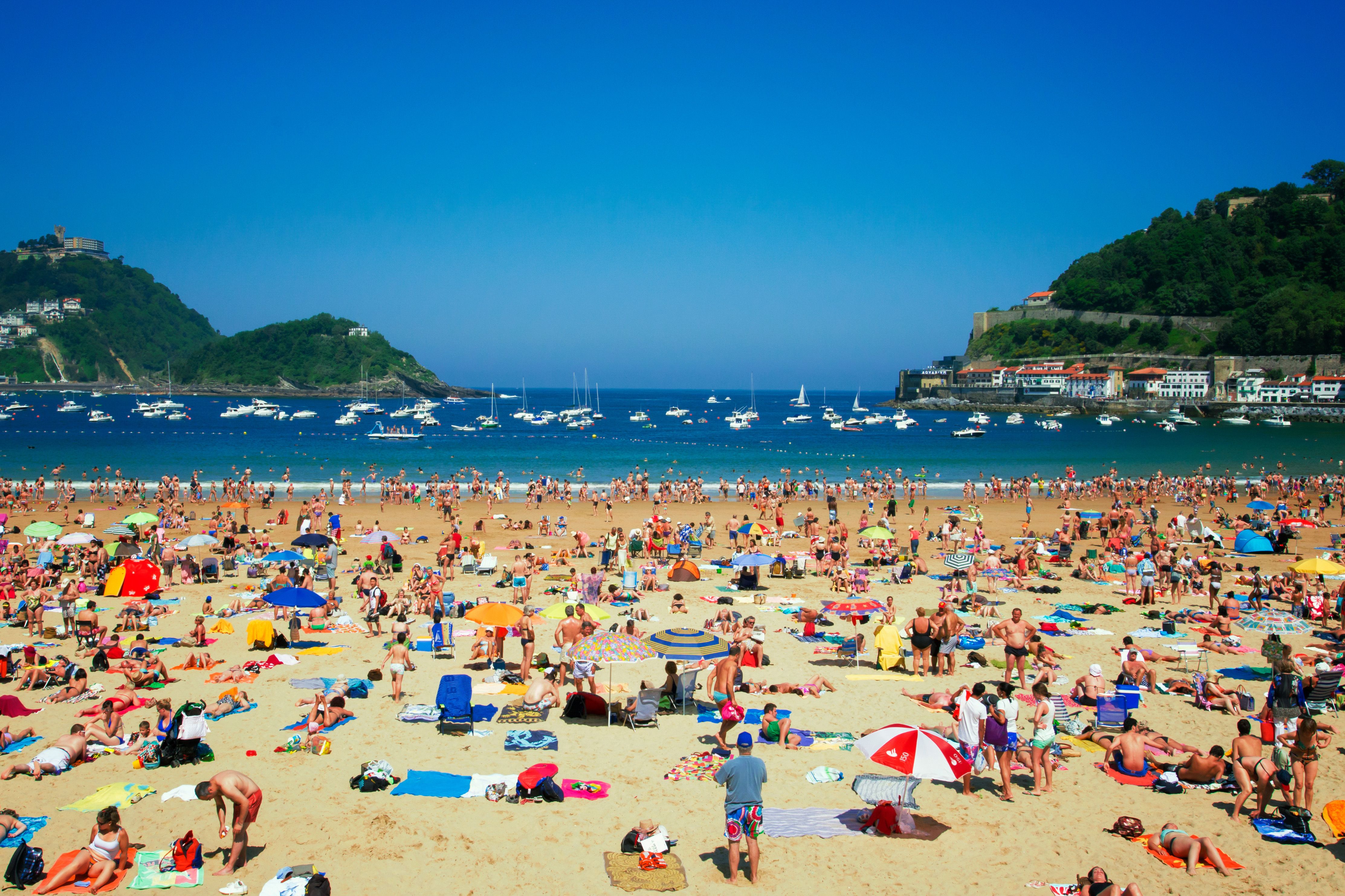 People relax on a sandy beach near the ocean.