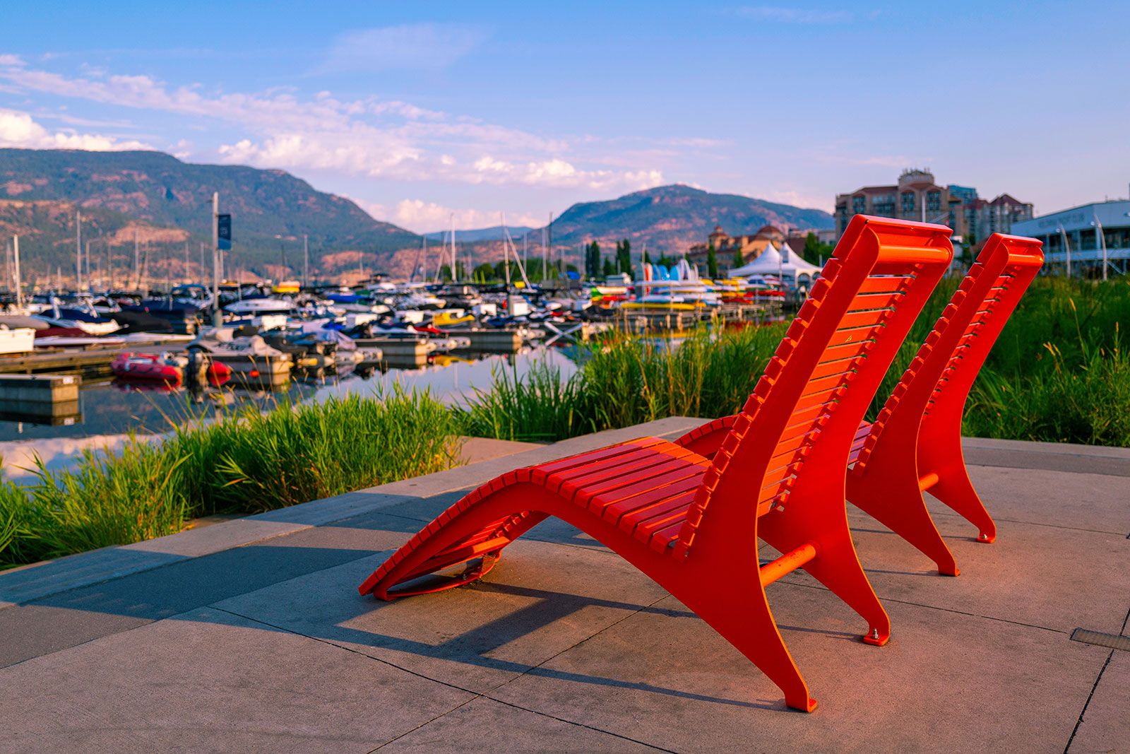 Two red chairs at a marina.
