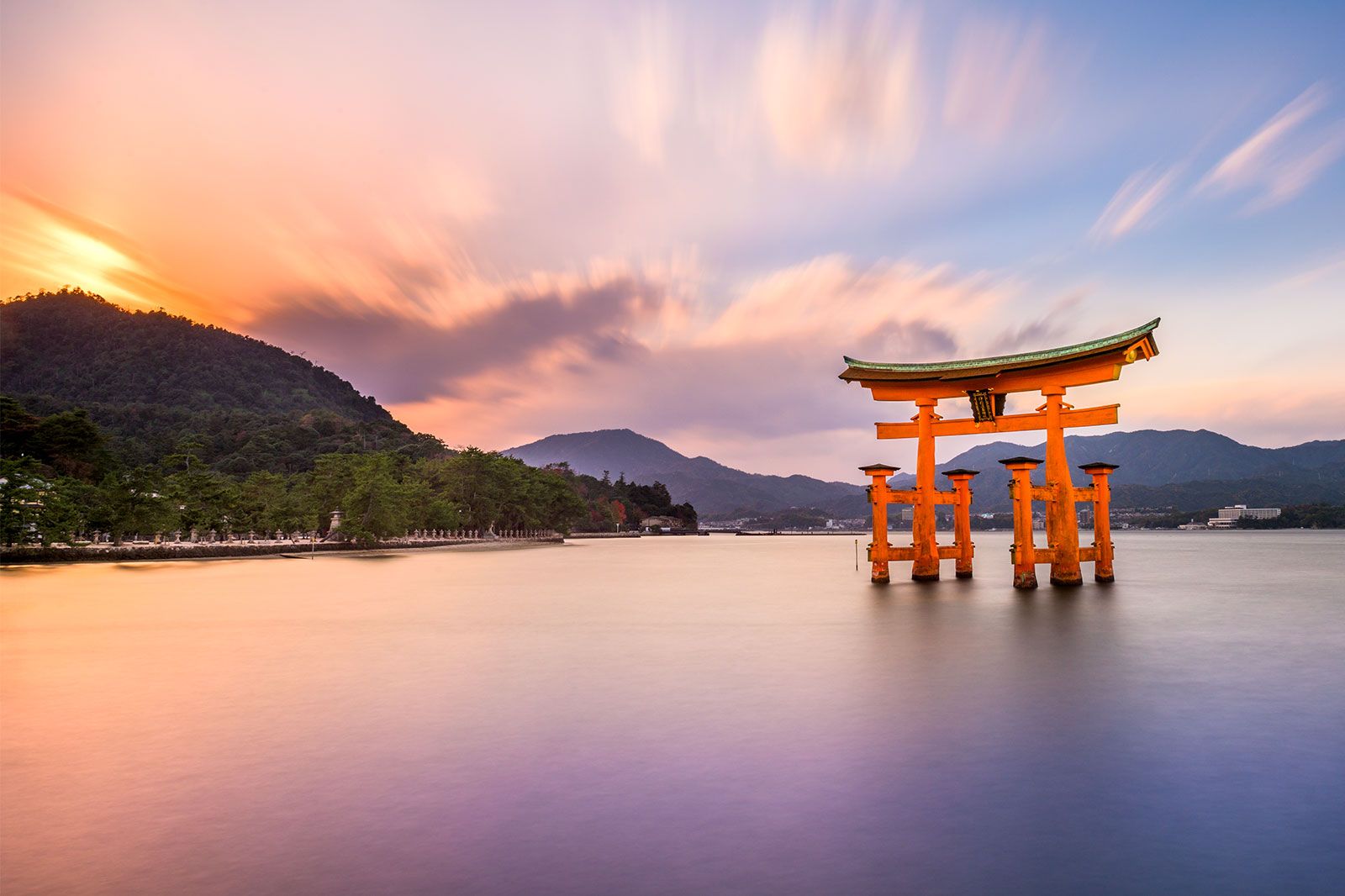 A red shrine above water in the middle of a lake at sunset.