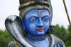 A statue of Shiva with blue face and body and a cobra around his neck.